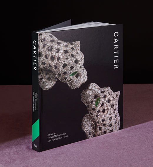 Hardback book cover of the V&A Cartier exhibition. A close up of the iconic Cartier diamond panther bangle is photographed against a lack background.